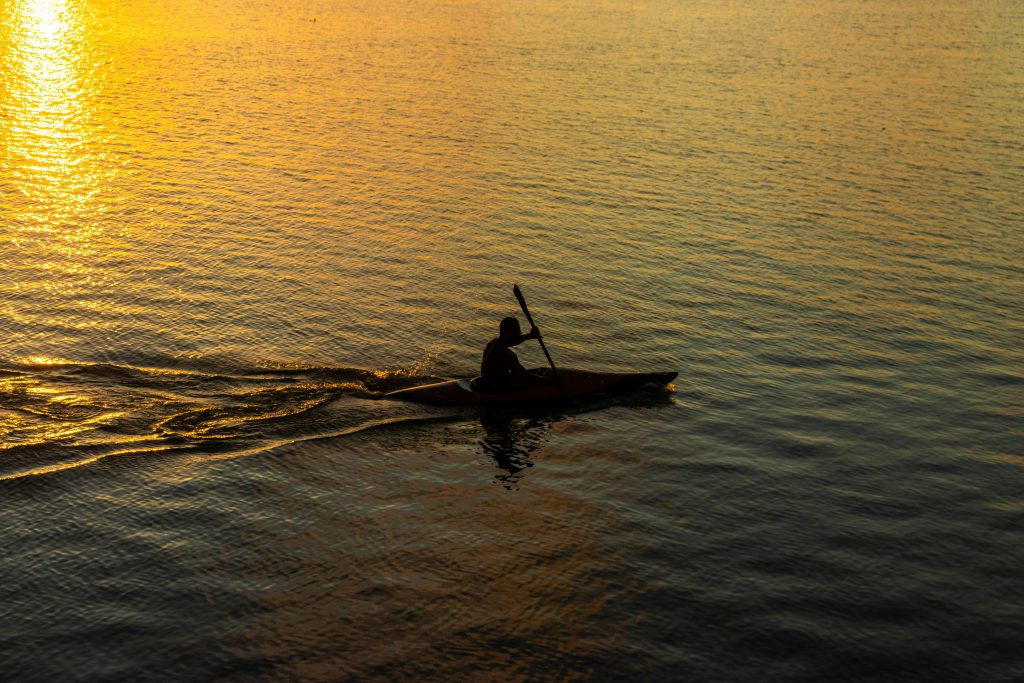 “Person kayaking on the Murray River at sunset, with golden reflections on calm water.”