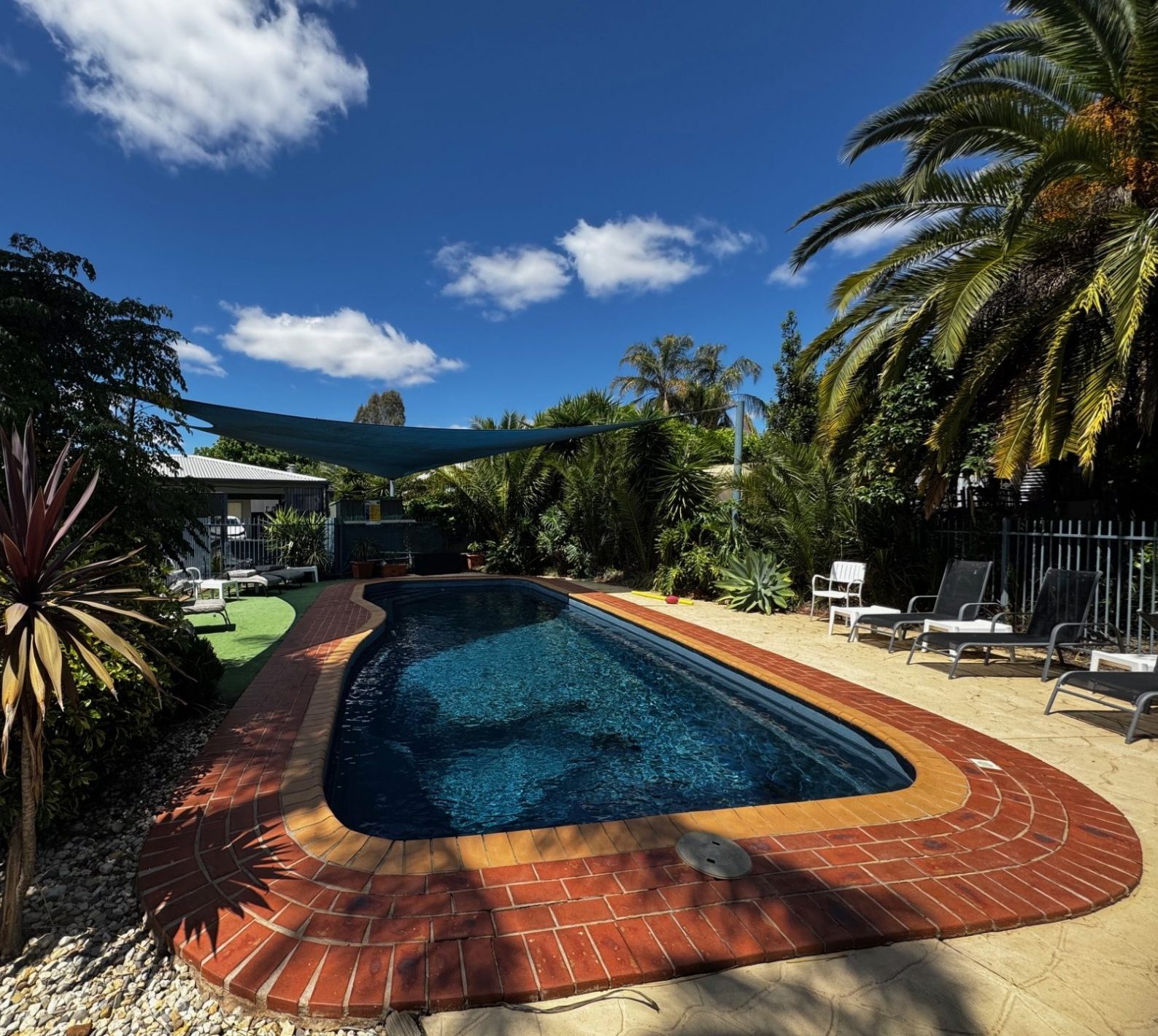 Outdoor pool area with shaded zones, chairs and tables