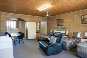 “Queen room at Sunrise Motel in Barooga, NSW, featuring one queen bed and two single beds, with recliner seating, dining area, and kitchenette.